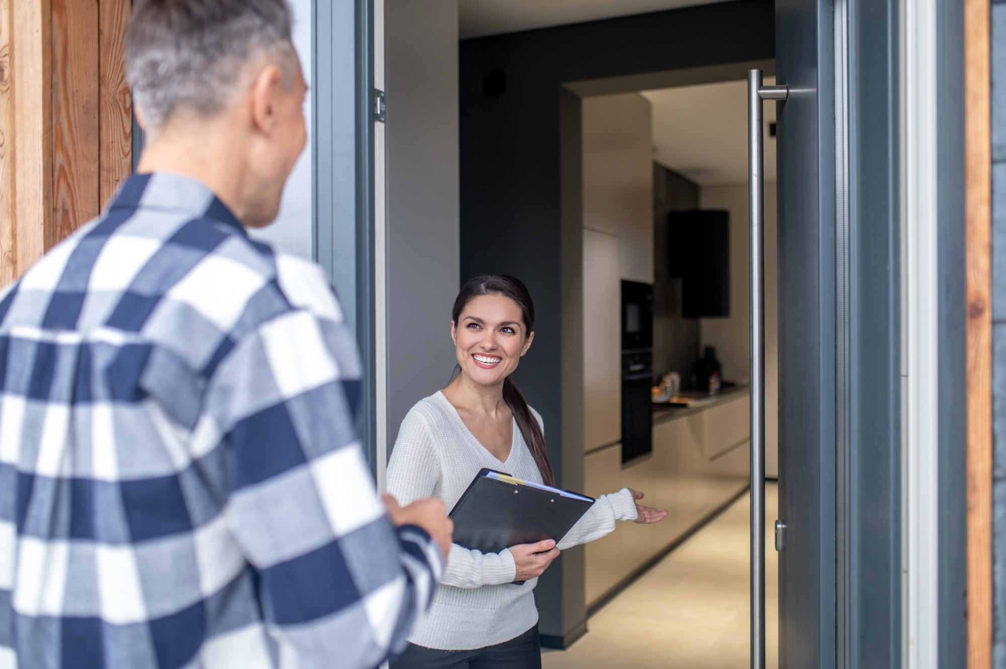 Consultora recebendo um cliente na porta de um apartamento para entregar o imóvel alugado